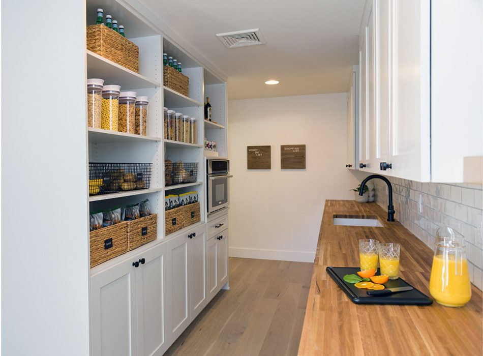 Organized pantry with open shelving, labeled baskets, and a wood countertop