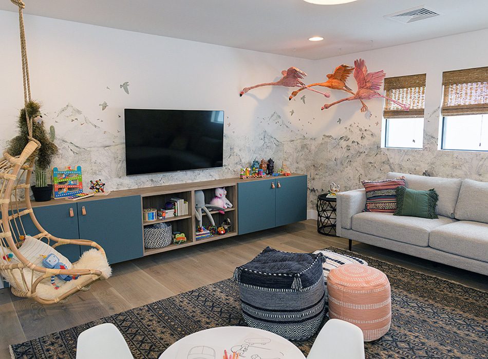 Playroom with a TV, storage cabinets, hanging chair, and flamingo decor