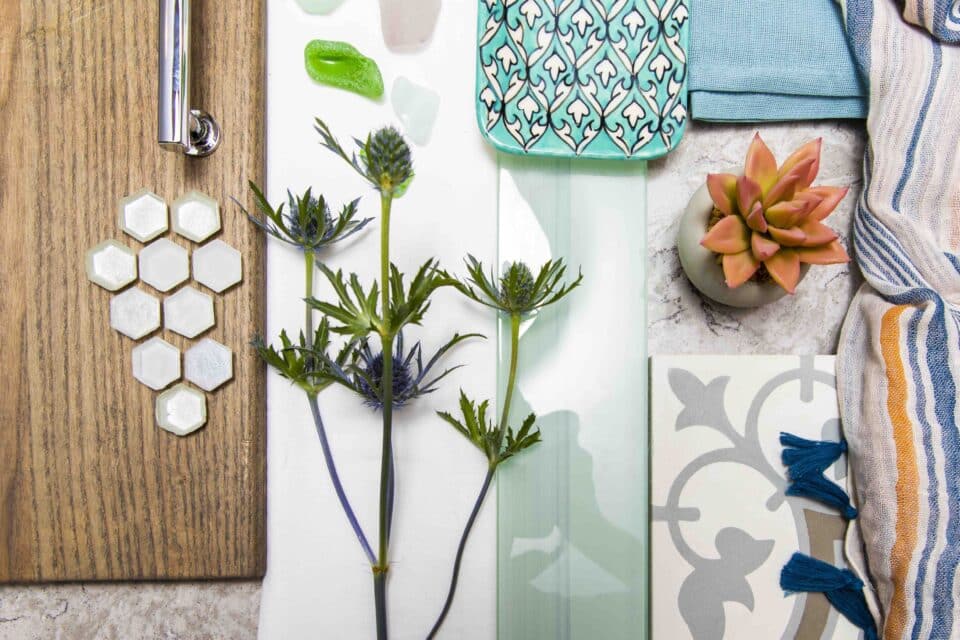 Flat lay of wood, tiles, fabric swatches, succulent, glass samples, and greenery