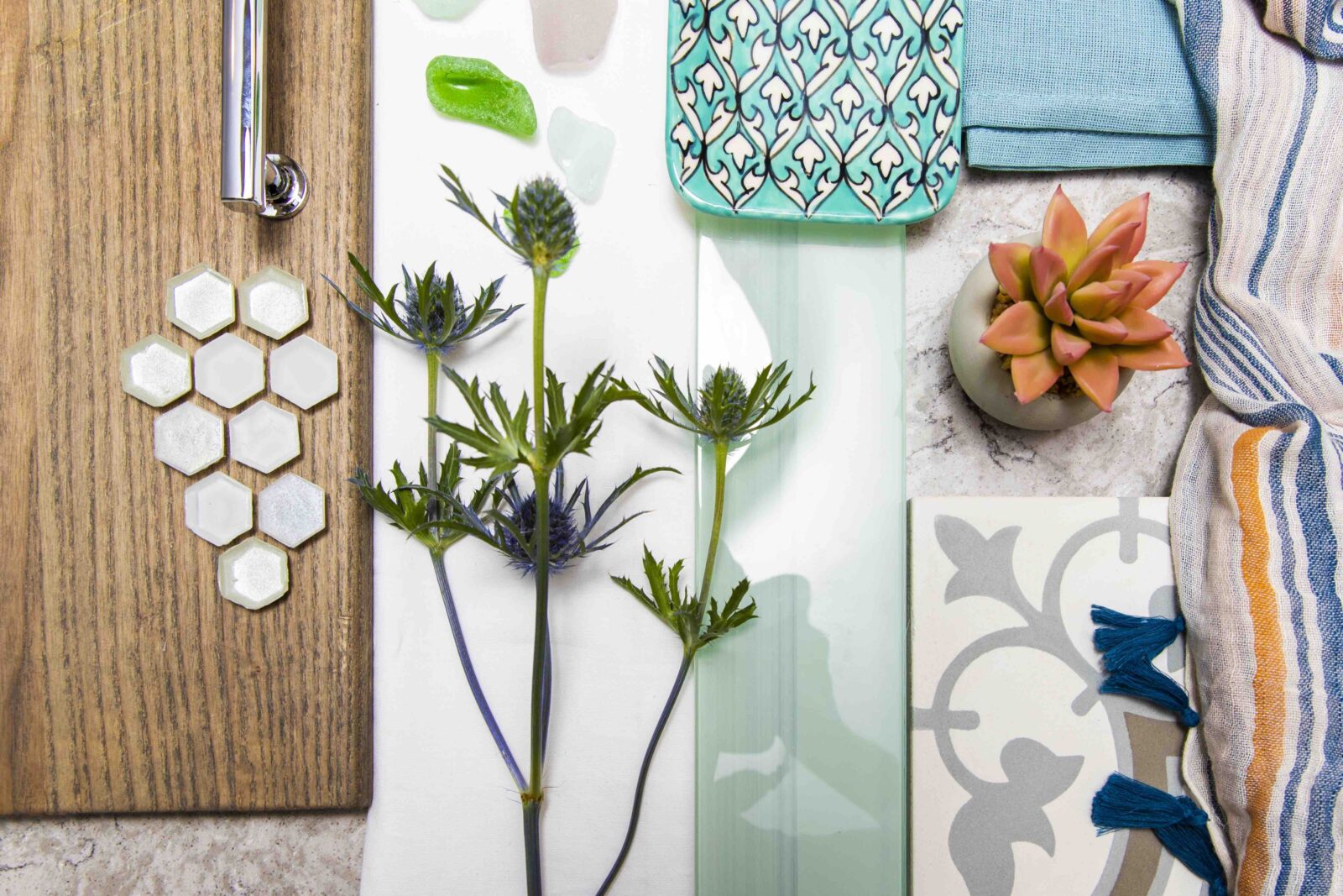 Flat lay of wood, tiles, fabric swatches, succulent, glass samples, and greenery