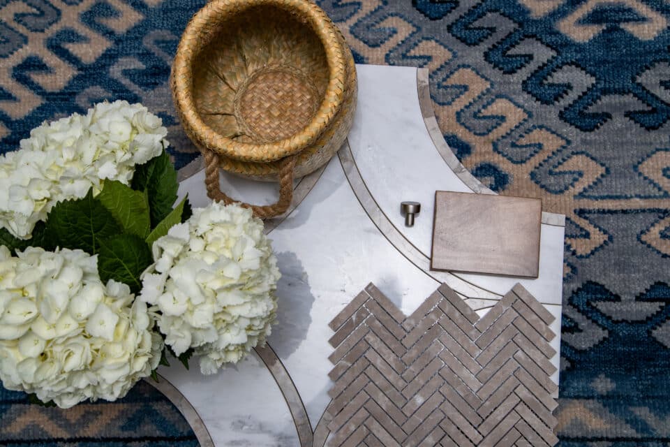 Flat lay with basket, hydrangeas, tile samples, and blue patterned rug