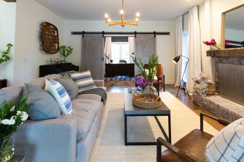 Living room with gray sofa, striped pillows, barn doors, brick fireplace, and modern decor