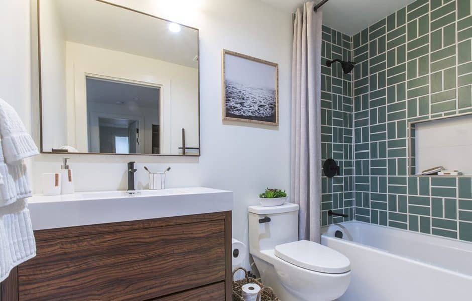 Bathroom with a white vanity, a large mirror, and a green tiled shower
