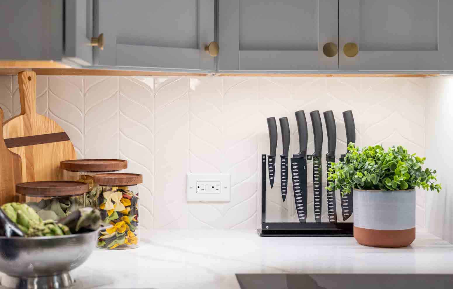 Kitchen counter with knife set, wooden cutting boards, glass jars, and potted plant