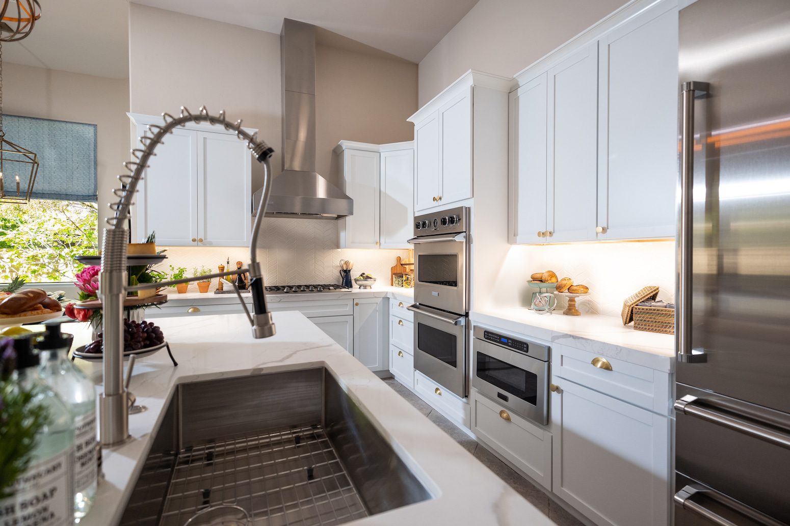 Modern kitchen with white cabinets, stainless appliances, and gooseneck faucet