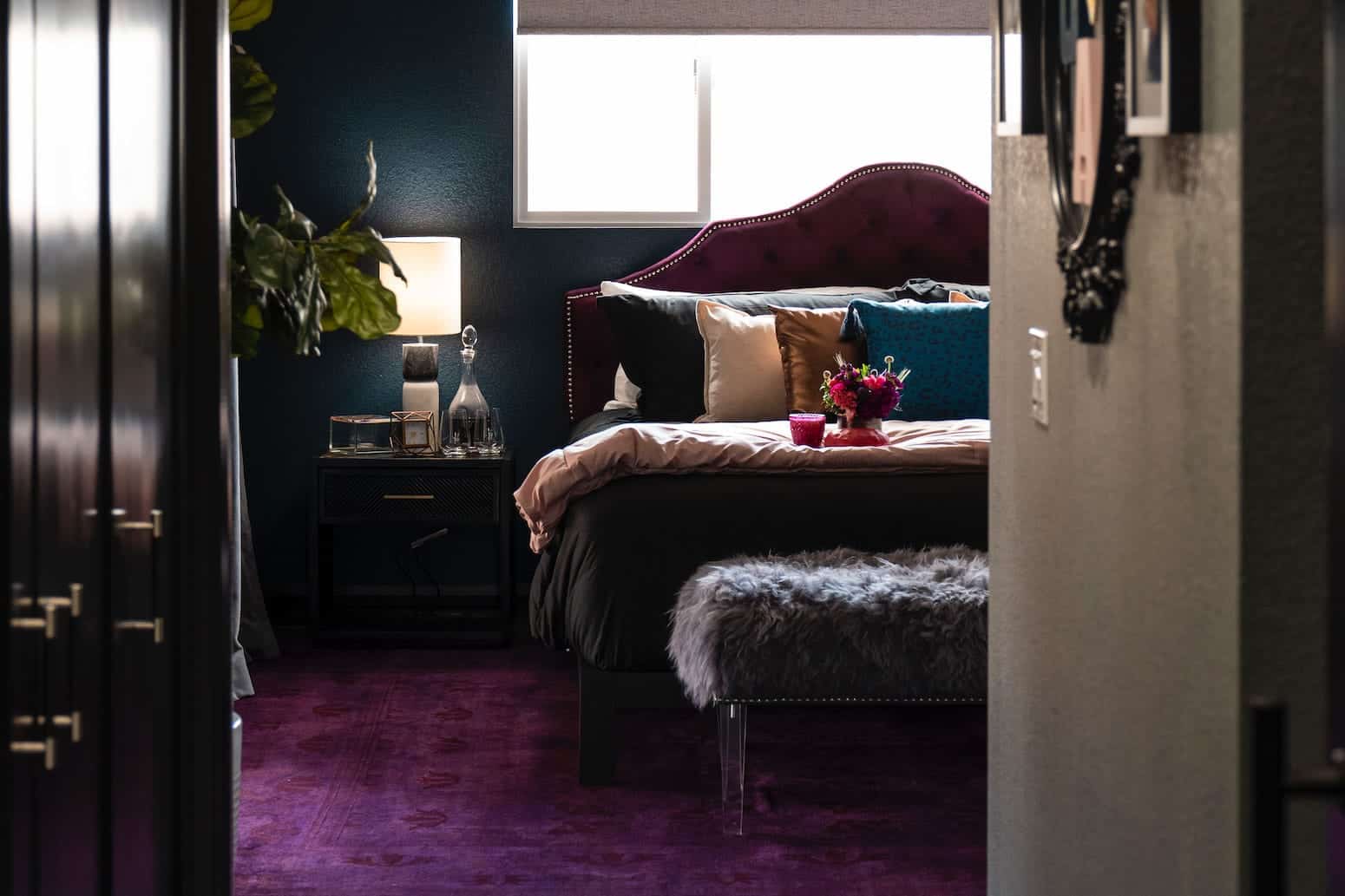 Cozy bedroom with dark walls, velvet headboard, plush bedding, and a purple rug