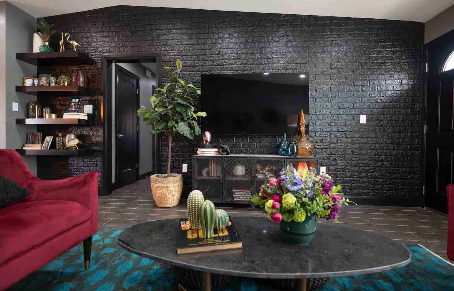 Modern living room with black brick wall, red seating, and wall-mounted TV