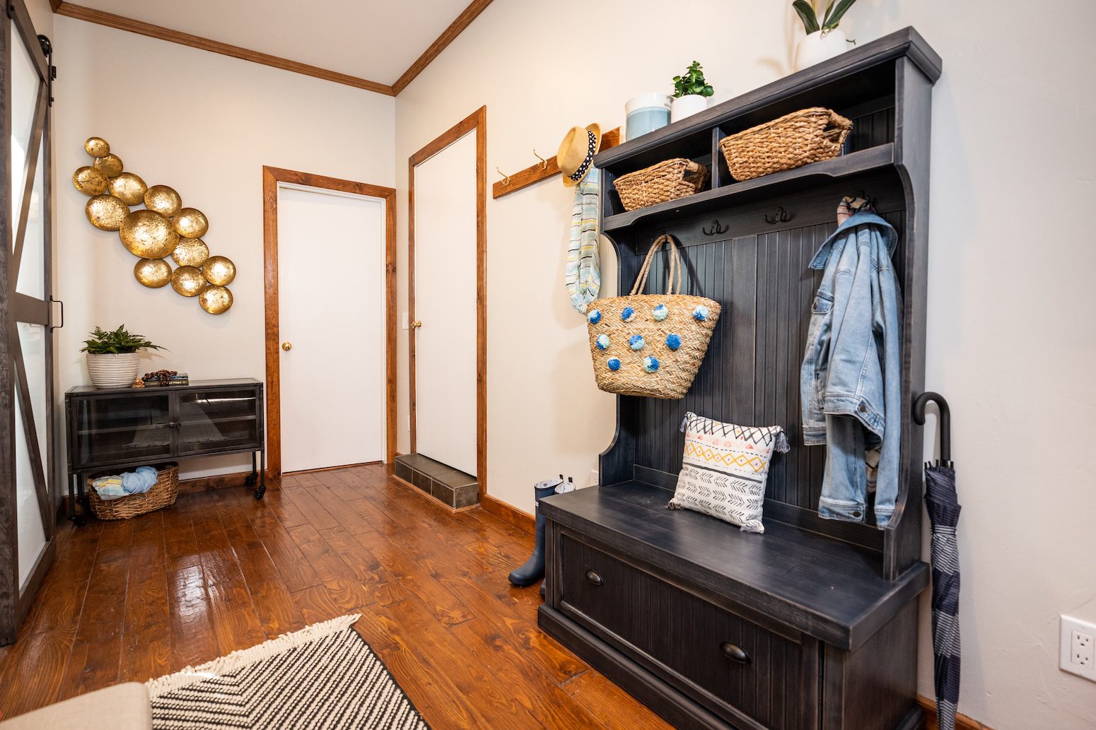 Mudroom with a black storage bench, woven baskets, and decorative wall accents