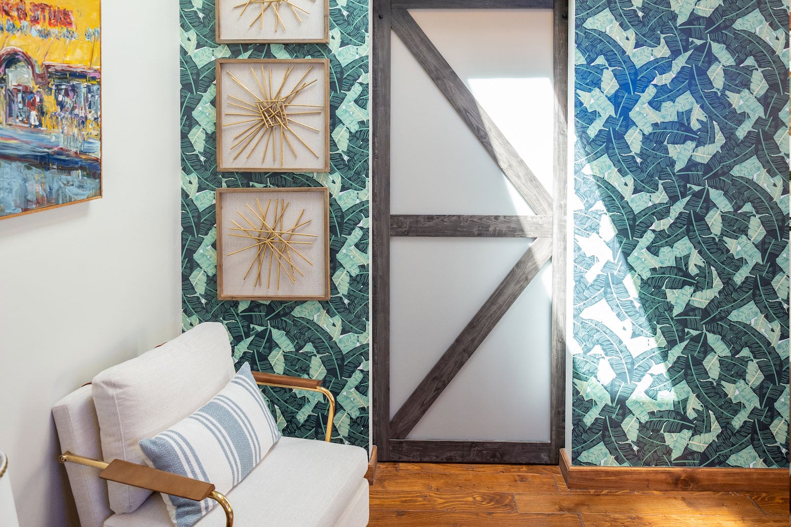 Corner with white armchair, green leaf wallpaper, and barn door