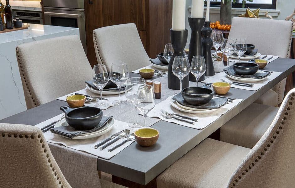 Elegant dining table set with black dinnerware, wine glasses, and modern candle holders