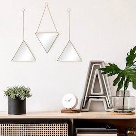 Shelf with three mirrors, plant, clock, and vase with leaves