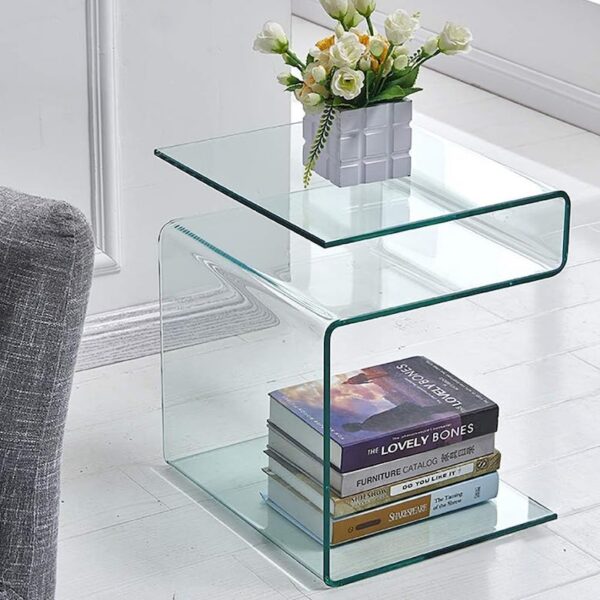 Curved glass side table with books on the bottom shelf and a flower arrangement on top