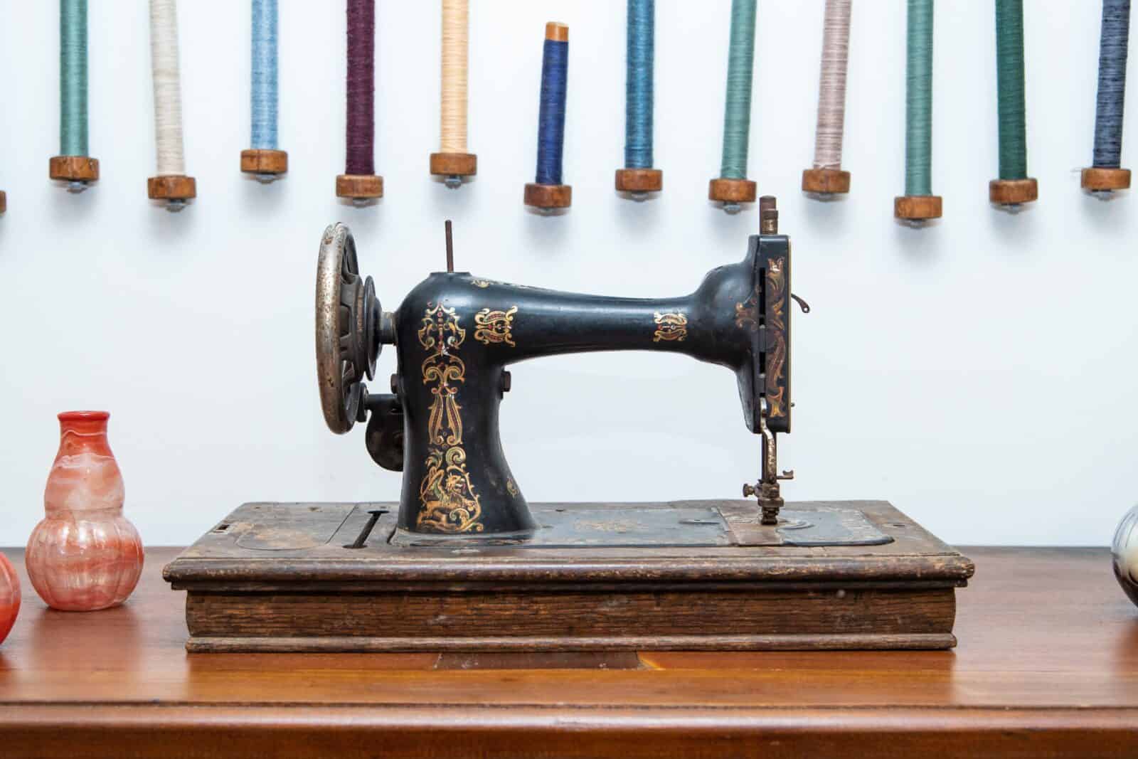 Antique Singer sewing machine with colorful spools of thread resting on a wooden table