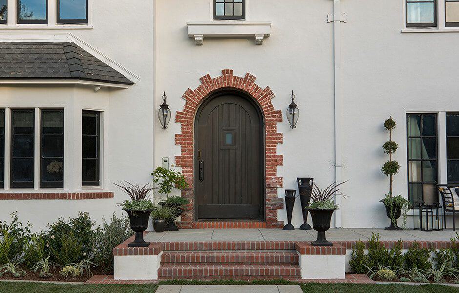 Elegant front entrance with brick archway, dark wooden door, and decorative planters