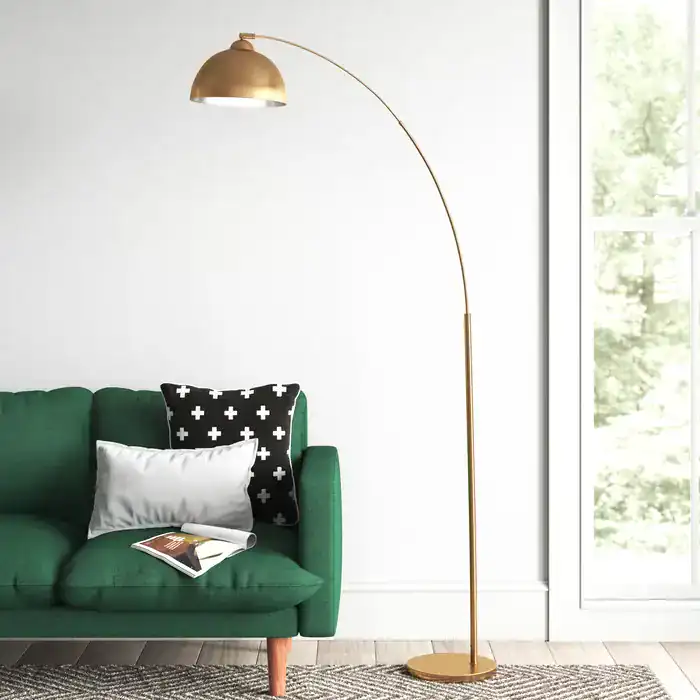 Modern living room with green sofa, gold arc floor lamp, and black and white pillows