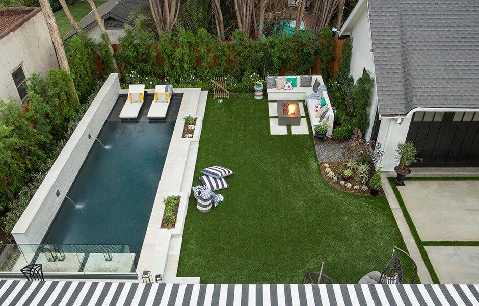 Beautifully landscaped backyard with a swimming pool, patio areas, and lush greenery