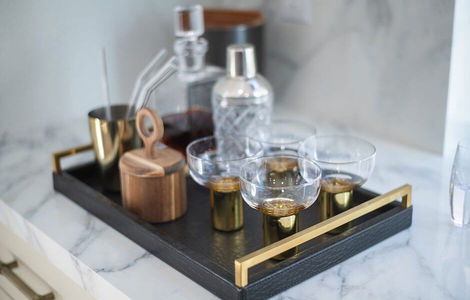 Bar tray with gold-rimmed glasses and cocktail accessories