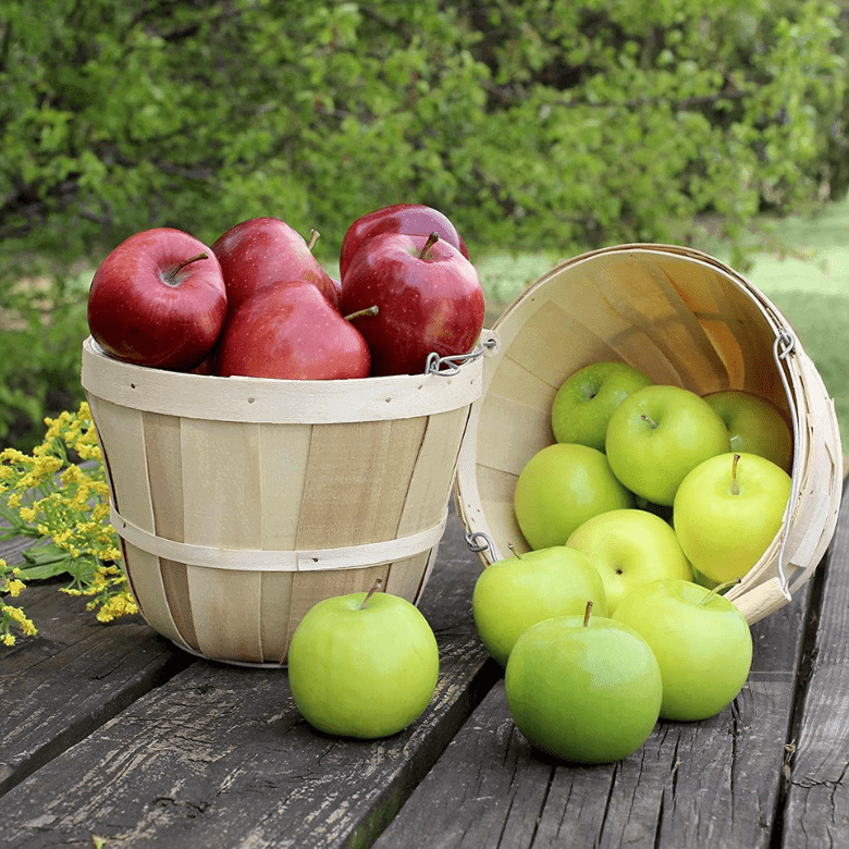 Wooden baskets filled with red and green apples on a rustic wooden table outdoors