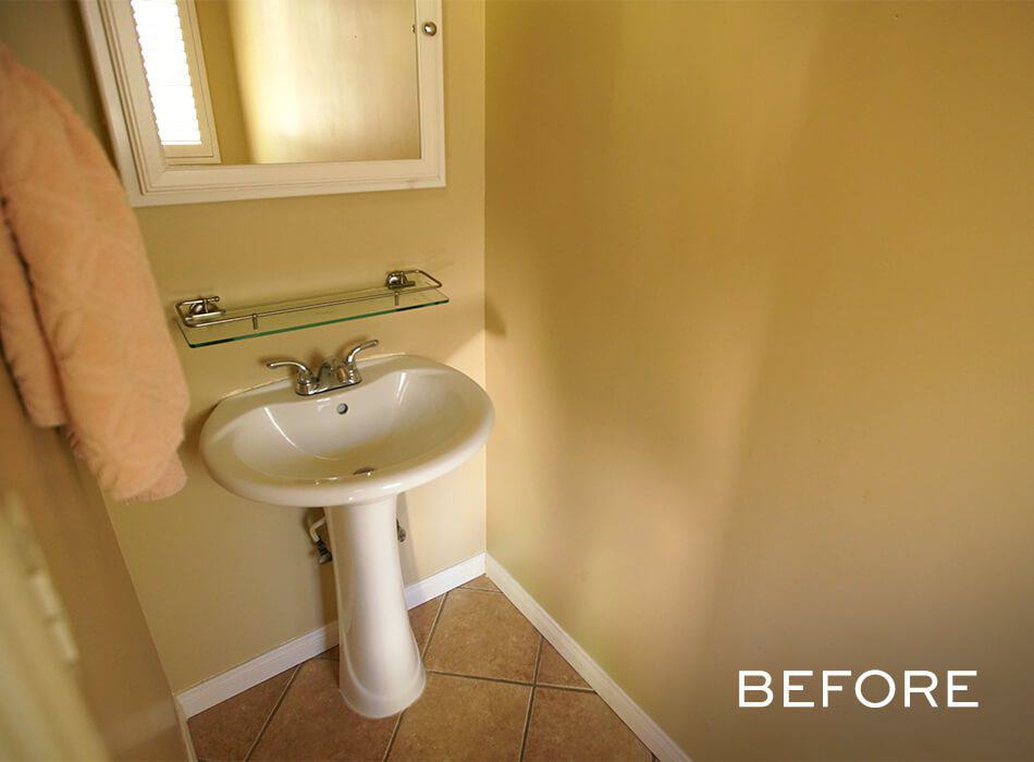 A before image of a small beige bathroom with a pedestal sink, glass shelf, and wall-mounted mirror