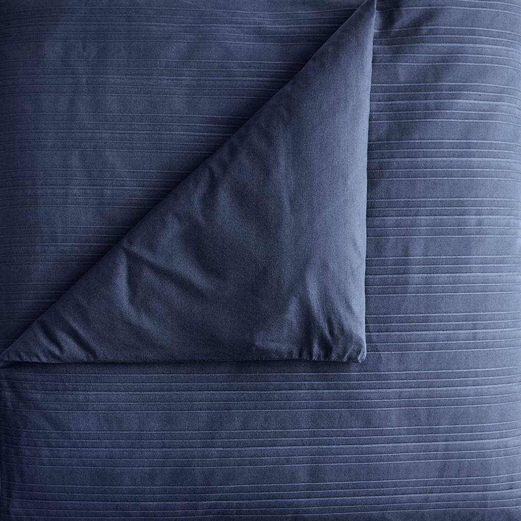 Dark blue textured duvet cover with subtle horizontal stripes and a corner folded back