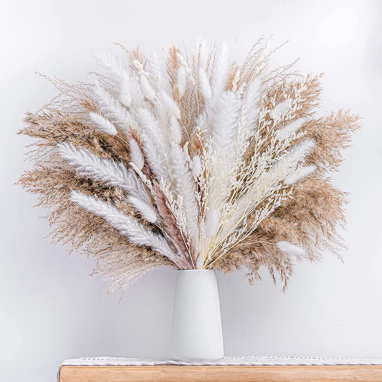 White vase filled with a large arrangement of dried pampas grass and soft white botanicals