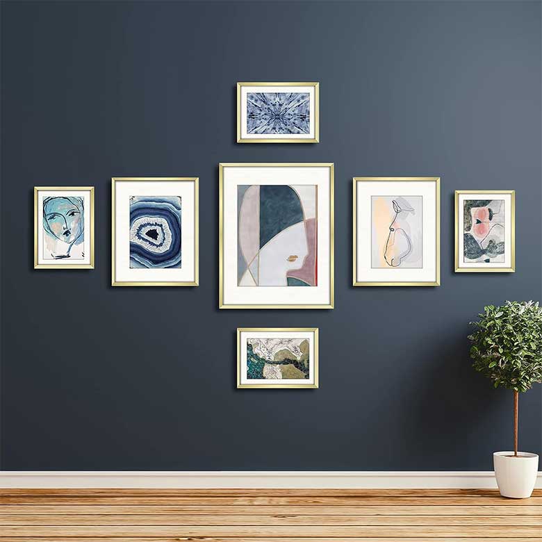 Symmetrical gallery wall with abstract art on dark blue wall