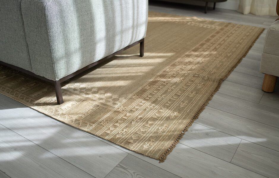 Textured beige area rug on light wood flooring beneath a modern sofa