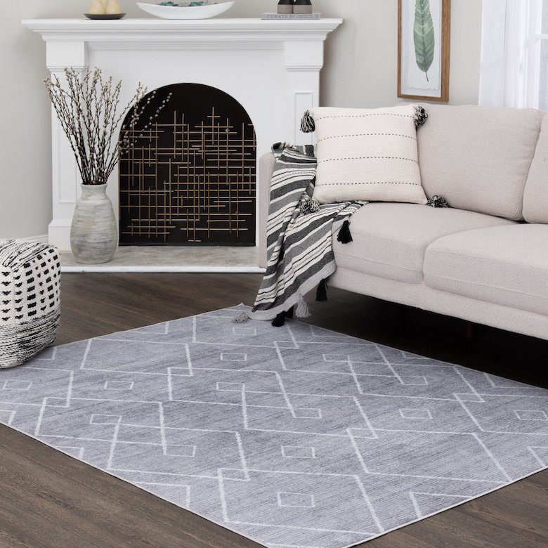 Modern living room with a geometric rug, neutral sofa, striped throw, and decorative fireplace
