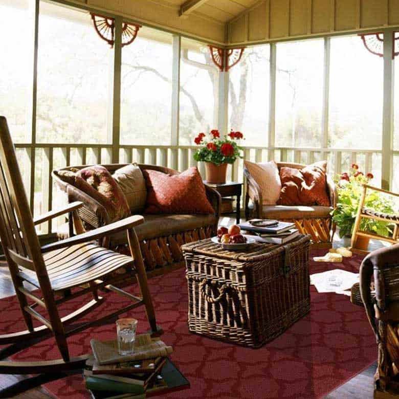 Cozy screened porch with wicker furniture rocking chair red rug and potted flowers