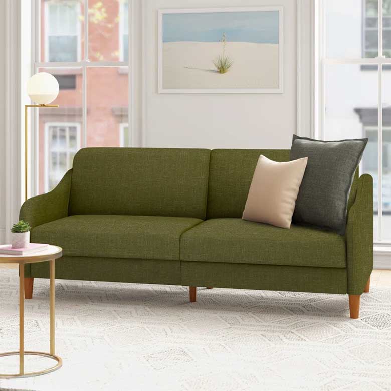 Green upholstered sofa with wooden legs and two accent pillows in a bright living room