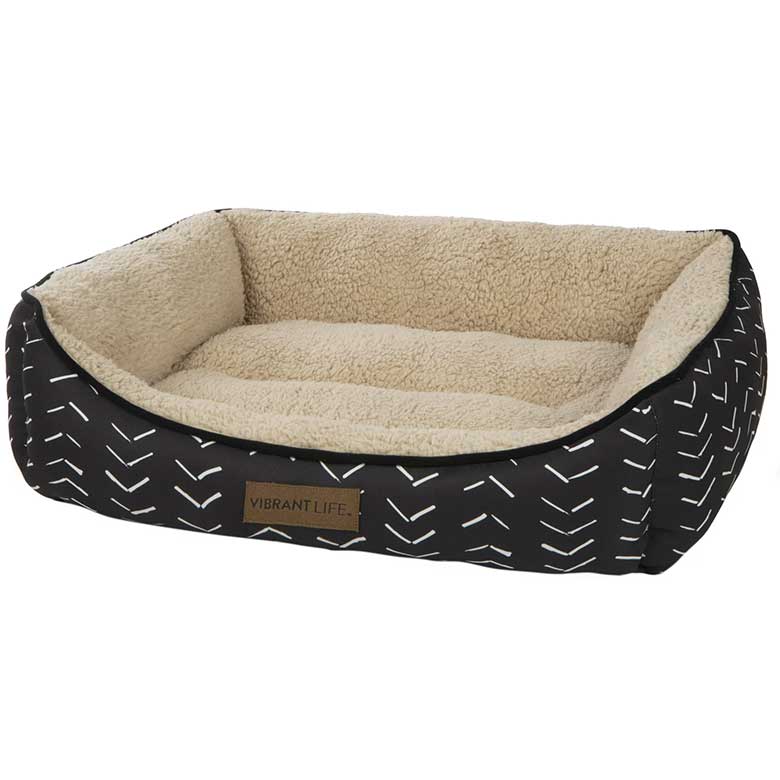 Black pet bed with white patterns and a beige fleece interior