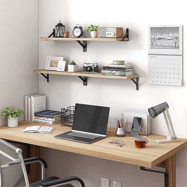 Minimalist home office with a wooden desk, wall shelves, and an open laptop