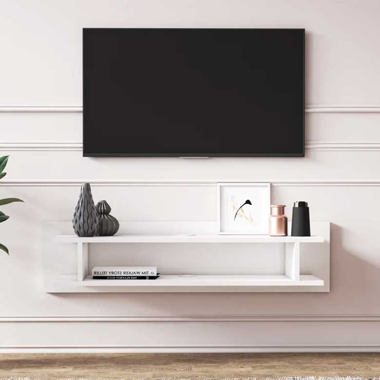 Wall-mounted TV above a sleek white floating shelf with minimal decorative items and a book