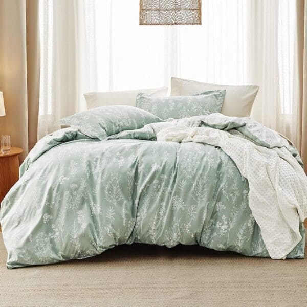 Soft green floral bedding with white pillows and cozy throws in a serene, light-filled bedroom