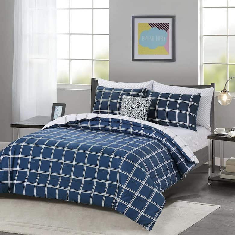 A blue and white plaid comforter set on a bed with a gray headboard