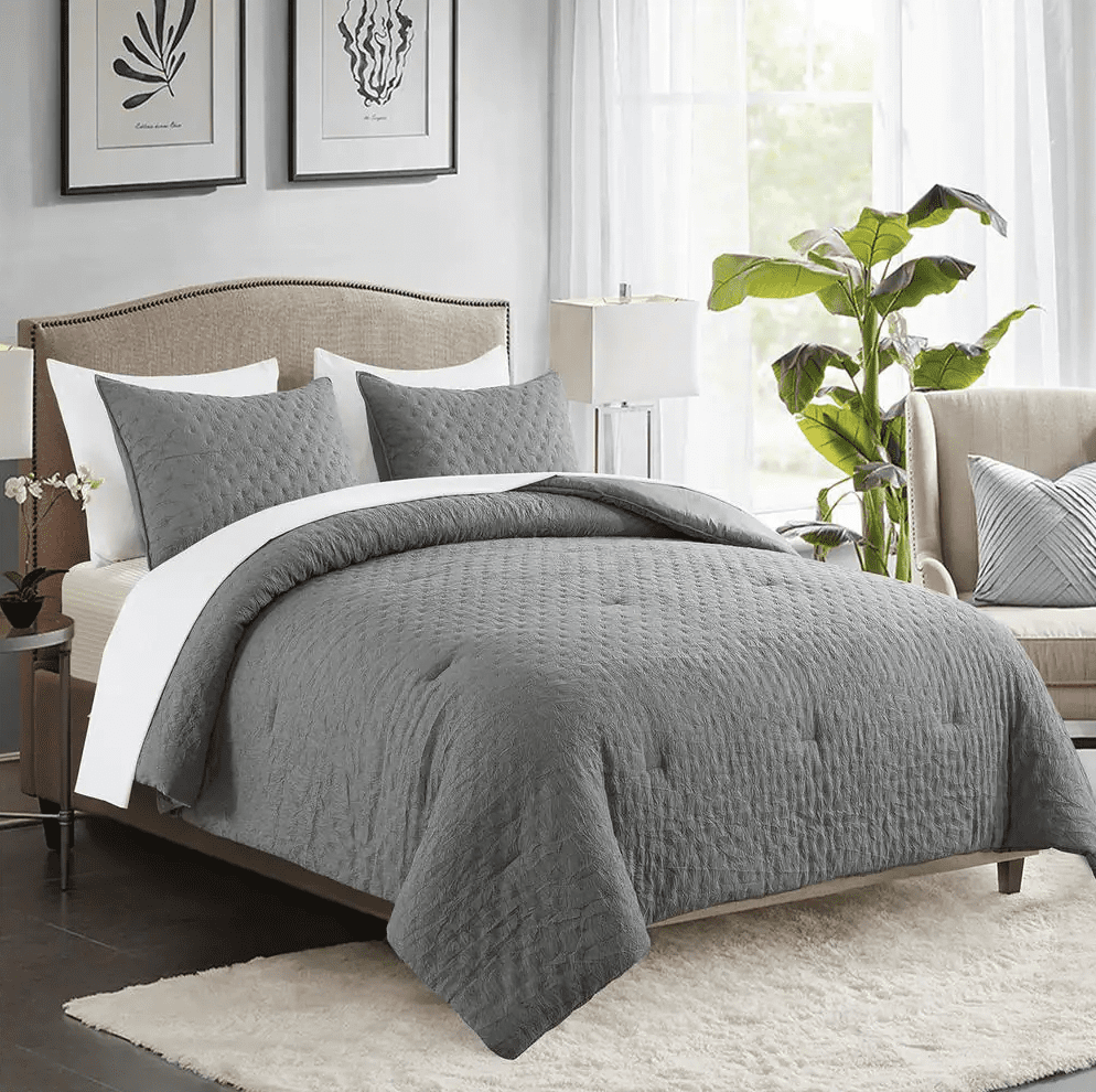 Modern bedroom with gray quilted bedding, beige headboard, and natural light from large windows