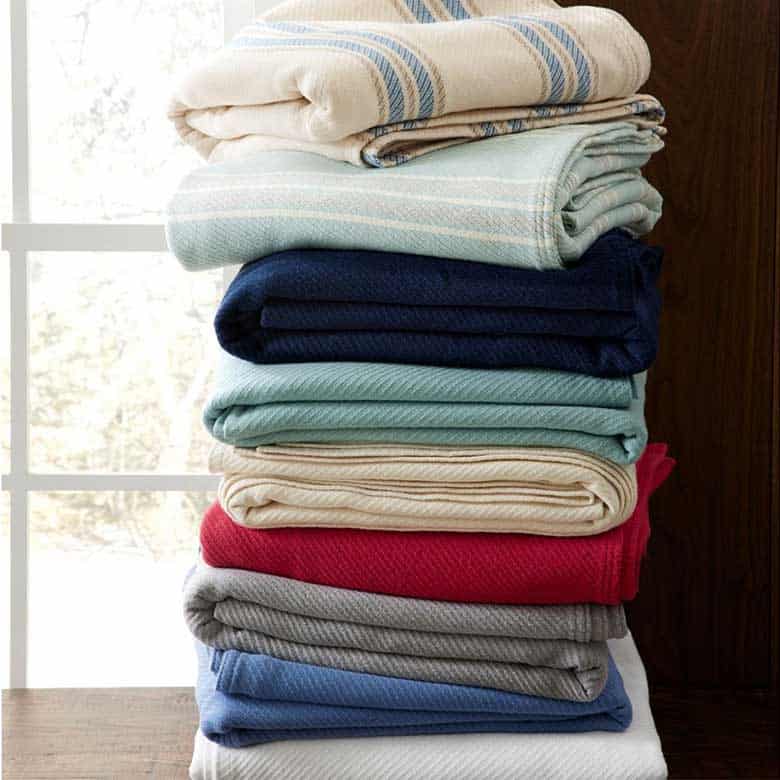 Stack of folded colorful blankets in various shades and patterns