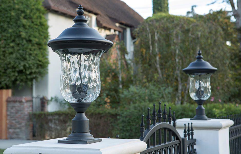 Black lantern-style gate lights with textured glass on a decorative fence