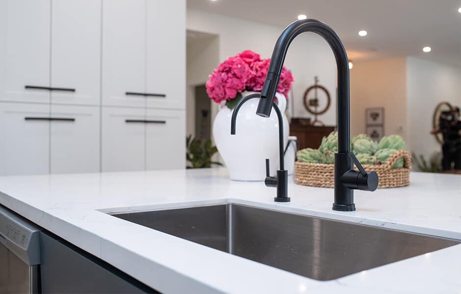 Modern kitchen sink with black faucet and white countertop