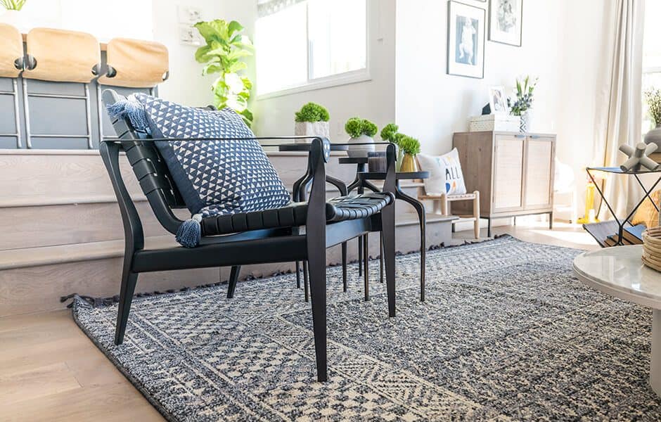 Cozy living room with a black chair, patterned rug, and potted plants