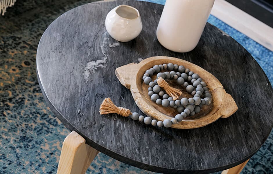 Black side table with vases and beaded garland in wooden tray
