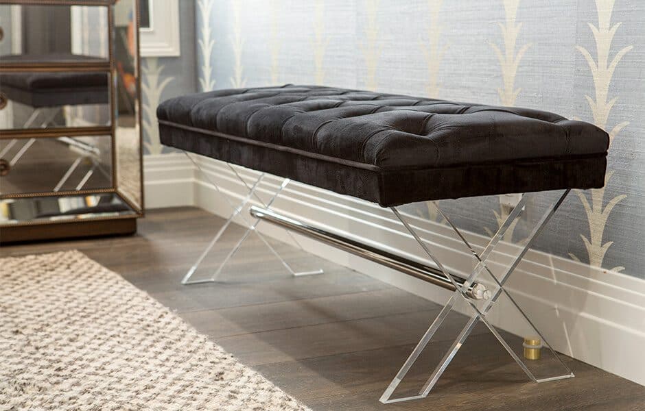Tufted black bench with clear acrylic legs in a modern room setting