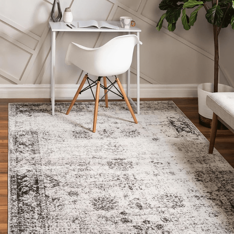 Modern home office with white desk, mid-century chair, and patterned area rug