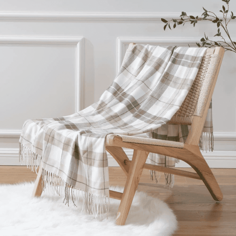 A cozy chair with a beige plaid blanket draped over it