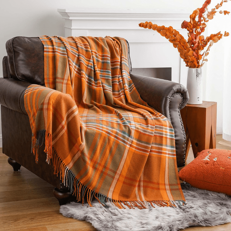 Leather chair with orange plaid blanket, pillow, and floral arrangement