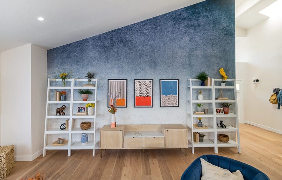 Living room with a blue ombre accent wall, white bookshelves, and modern artwork