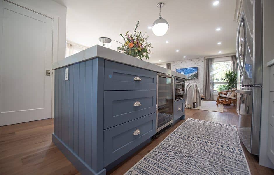 Kitchen island with blue cabinets, quartz countertop, and integrated appliances in an open-concept living space