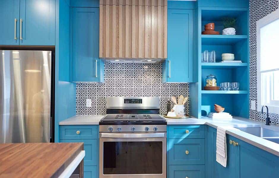 Bright blue kitchen cabinets with stainless steel appliances and patterned backsplash