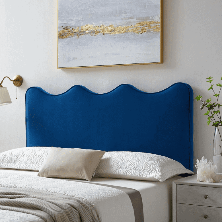 Bedroom with a scalloped blue headboard, white bedding, a gold-accented wall lamp, and abstract artwork above