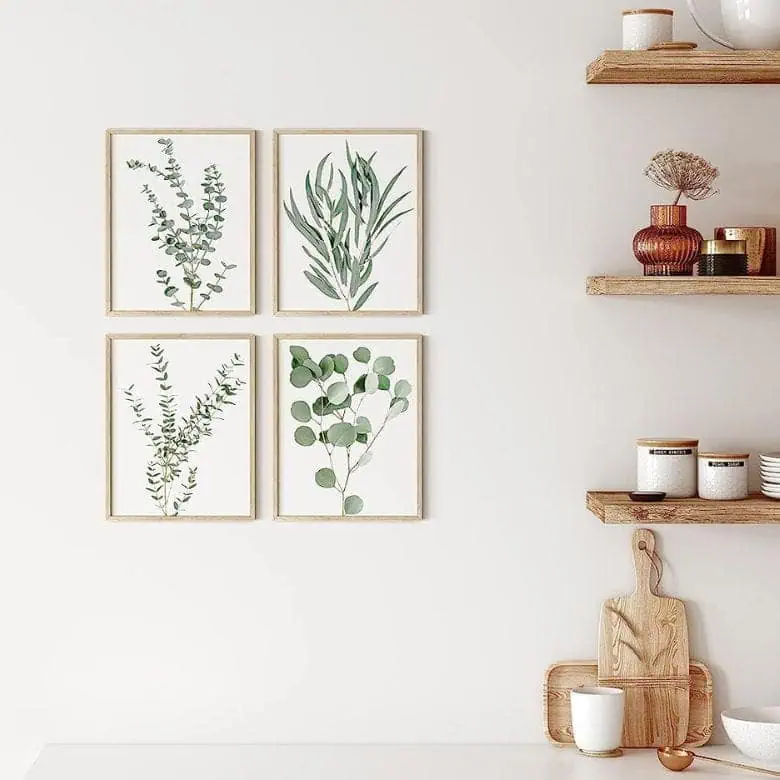 Wall with four framed botanical prints beside wooden shelves holding jars, bowls, and decor items